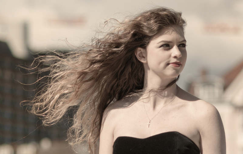 kvinde med sort kjole og håret blæsende i vinden